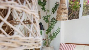 Una sala de estar acogedora con una mesa de centro de madera, un sofá con cojines a rayas y diversas plantas en macetas.