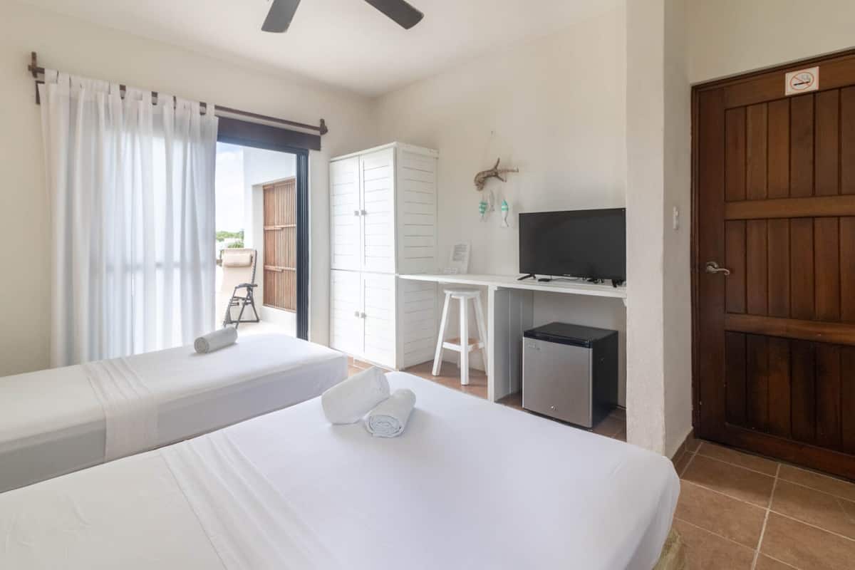 A hotel room with two beds, a desk, a television, and a wardrobe.
