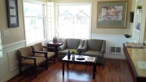 A living room with two armchairs, a sofa, a coffee table, and a painting on the wall. - Holiday Lodge (Port Angeles)