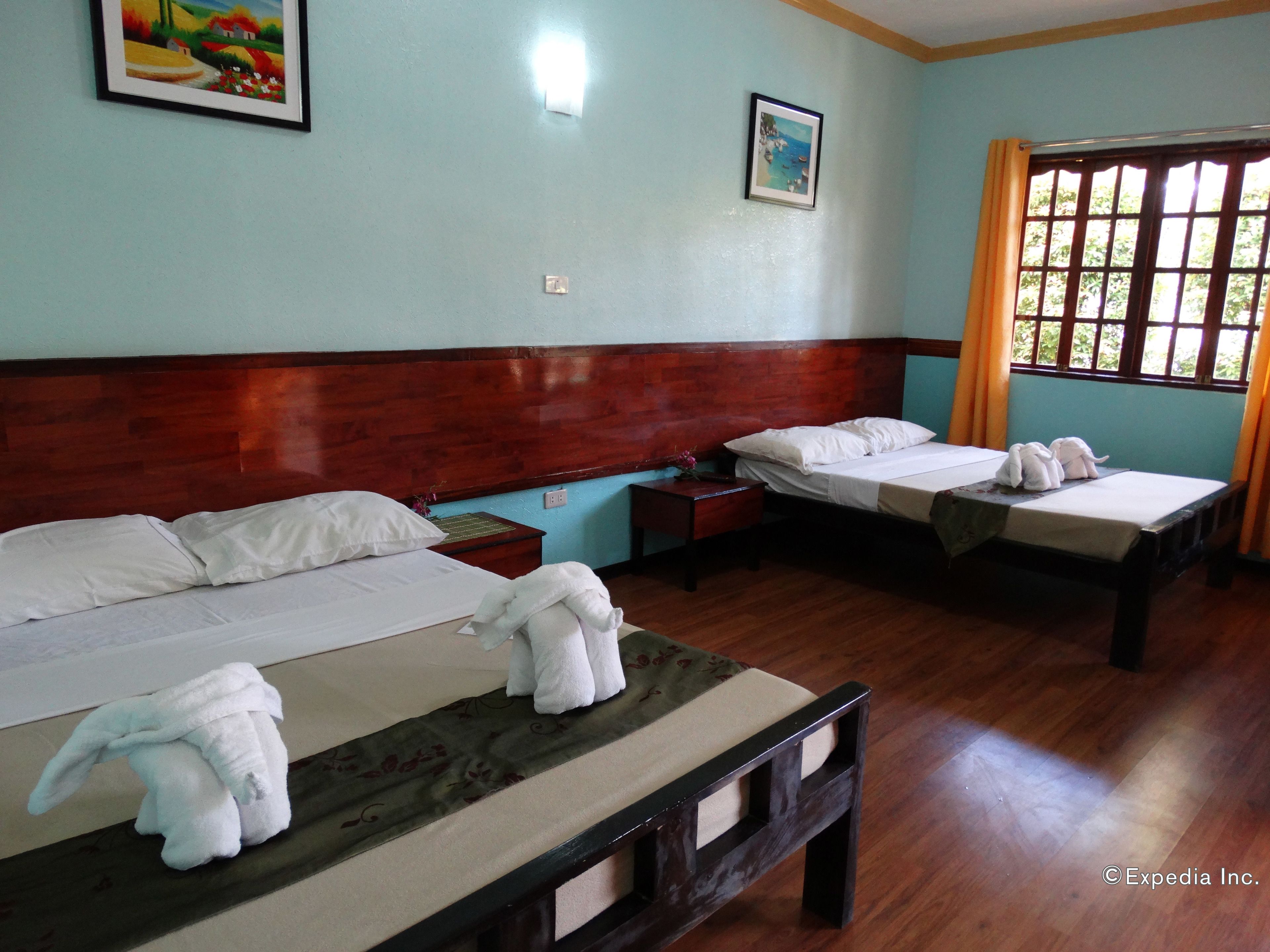 A hotel room with two beds, wooden headboards, and a large window with curtains.