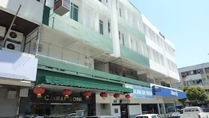 A multi-story building with a green awning, a visible hotel sign, and a clinic sign. - Cathay Hotel (Kota Kinabalu)