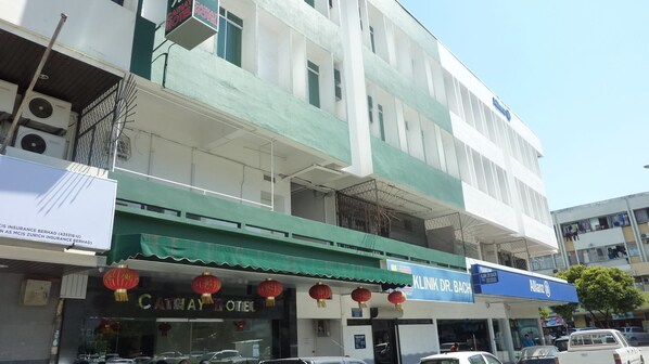 A multi-story building with a green awning, a visible hotel sign, and a clinic sign.