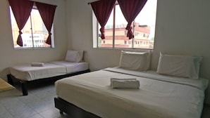 Une chambre d’hôtel avec deux lits, une fenêtre avec des rideaux et une vue sur les bâtiments environnants.
