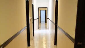 Un couloir au sol carrelé, avec des portes de part et d’autre.