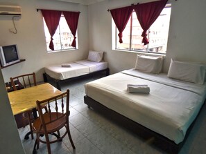 A hotel room with two single beds, a wooden table, a chair, and a TV on the wall. - Abell Residence (Kuching)