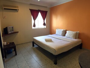 A hotel room with a bed, a small table with a television, a window with curtains, and an air conditioning unit. - Abell Residence (Kuching)