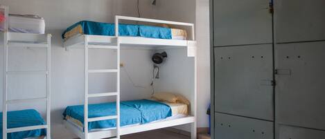 A dormitory room with bunk beds, a ceiling fan, and a green locker.
