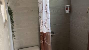 A small bathroom with a toilet, shower, and a curtain.
