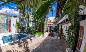 A courtyard with a swimming pool, potted plants, and a stone pathway. - Island Life Hostel (Santo Domingo)