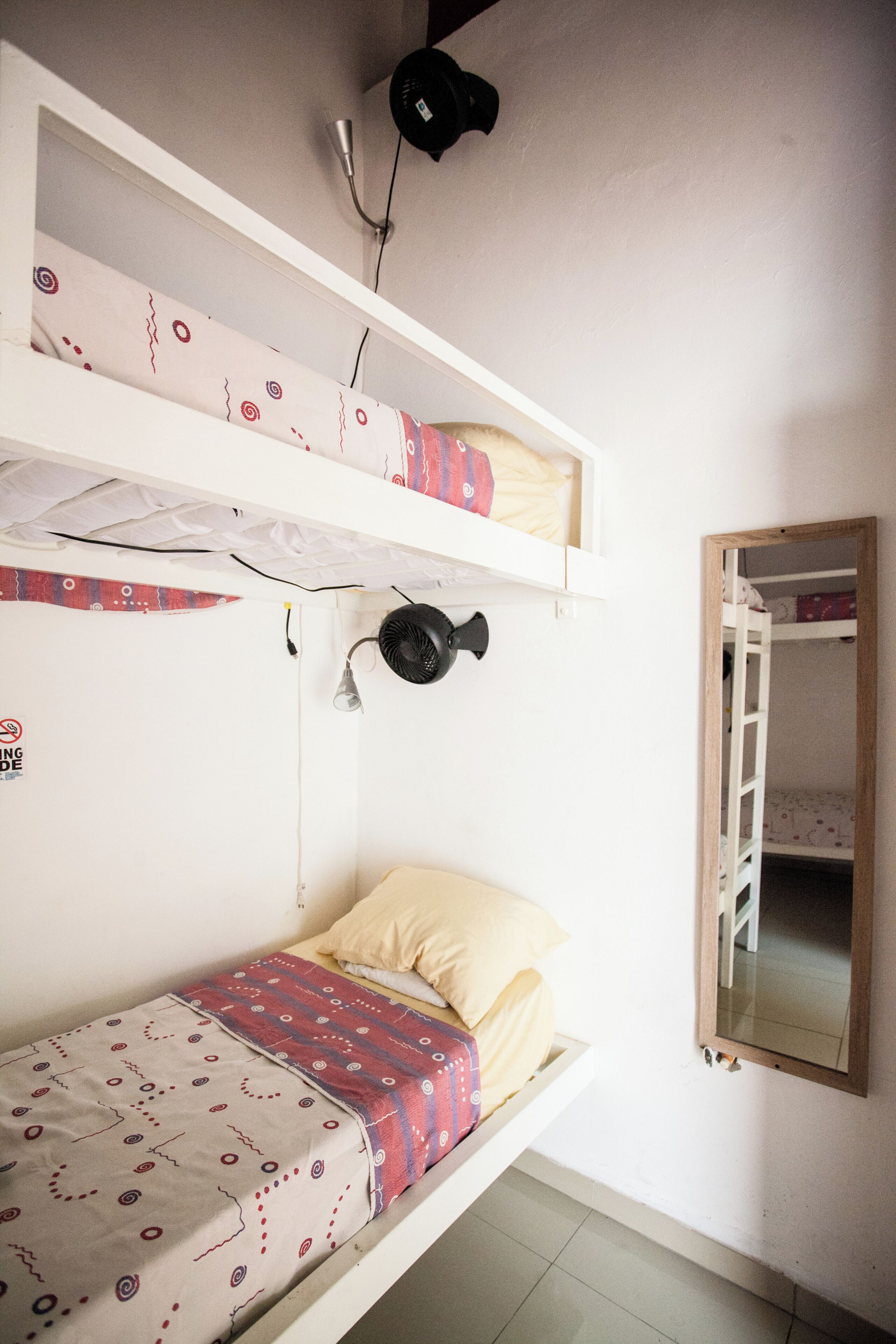A bunk bed room with a mirror, a heater, and a bed with patterned bedding.