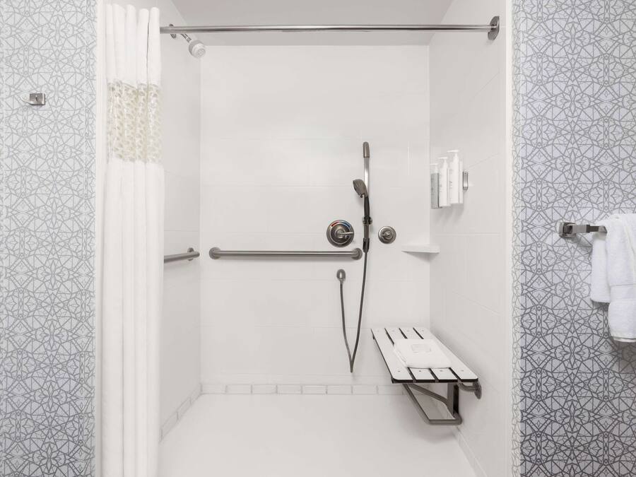 A shower area with a glass door, a towel rack with towels, and a shower control panel.