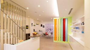 A modern reception area with a staircase, a reception desk, and a seating area with chairs. - The Crystal Inn Sun Moon Lake (Yuchi)