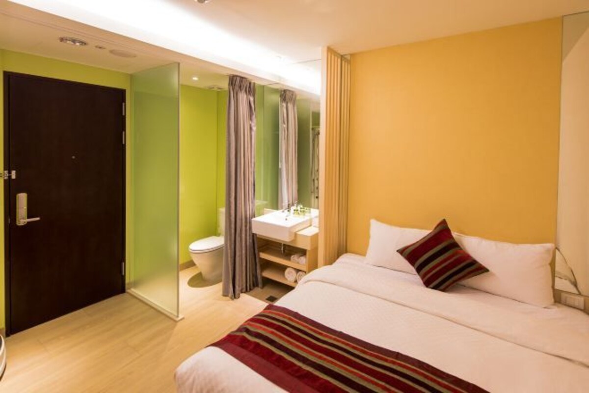 A hotel room with a bed, a bathroom, and a door.