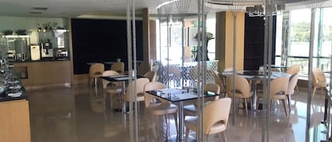 Een moderne eetruimte met tafels en stoelen, een bar en grote ramen voor natuurlijk licht.