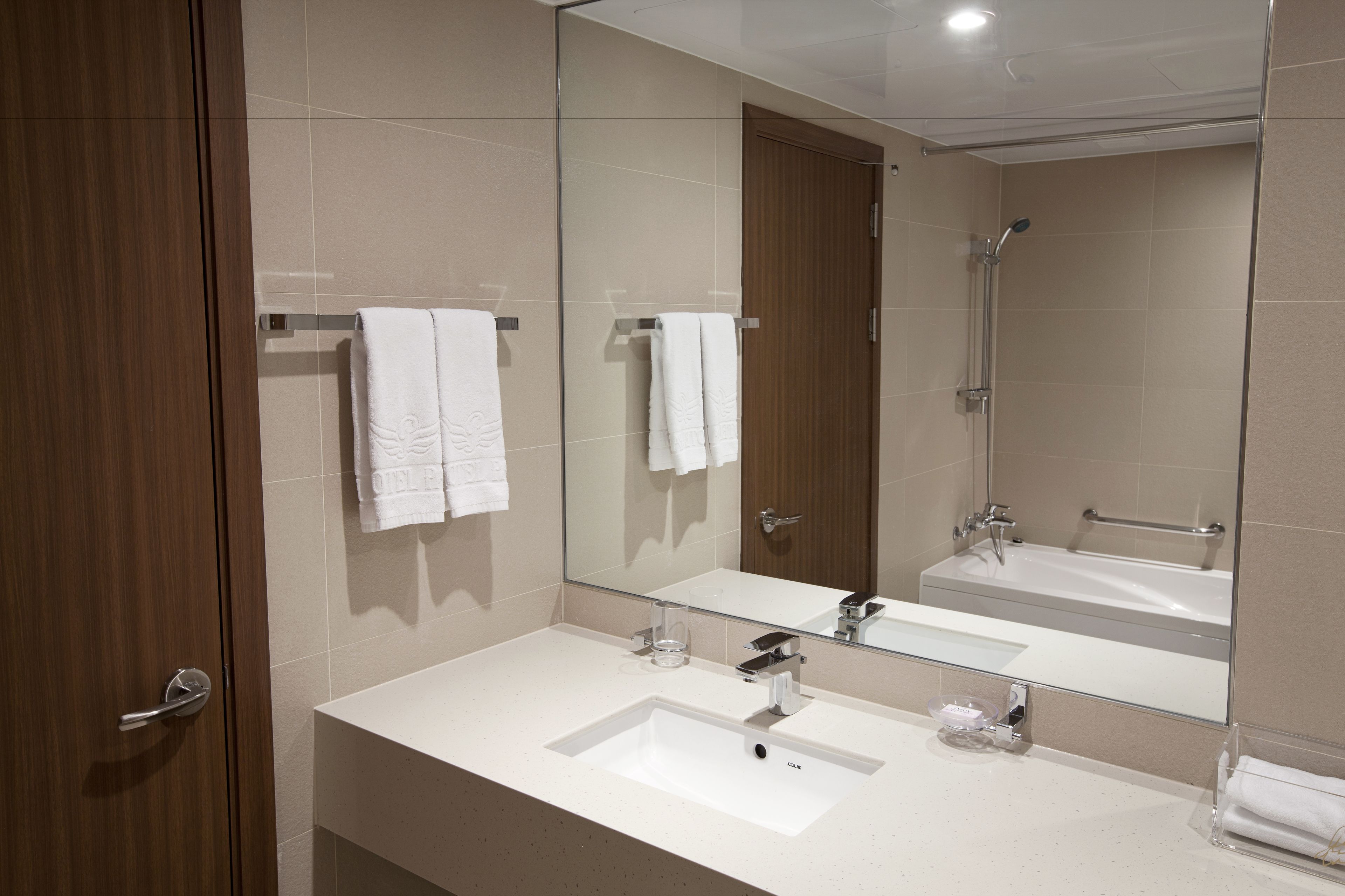 A modern bathroom with two sinks, a large mirror, and a shower.