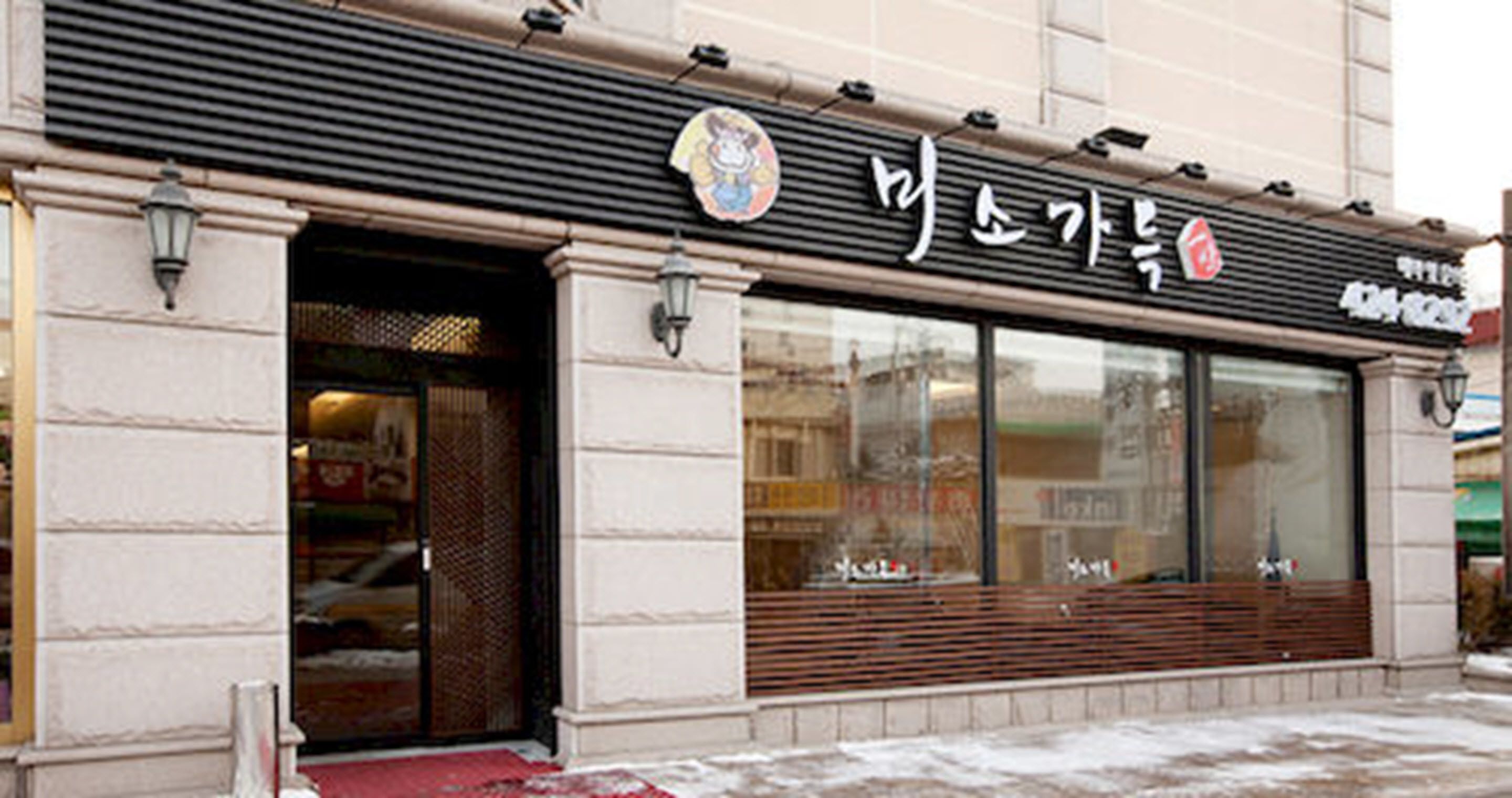 A storefront with a large glass window, a metal awning, and a sign with Korean characters.
