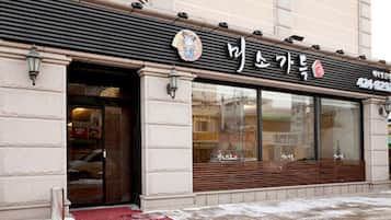 A storefront with a large glass window, a metal awning, and a sign with Korean characters.