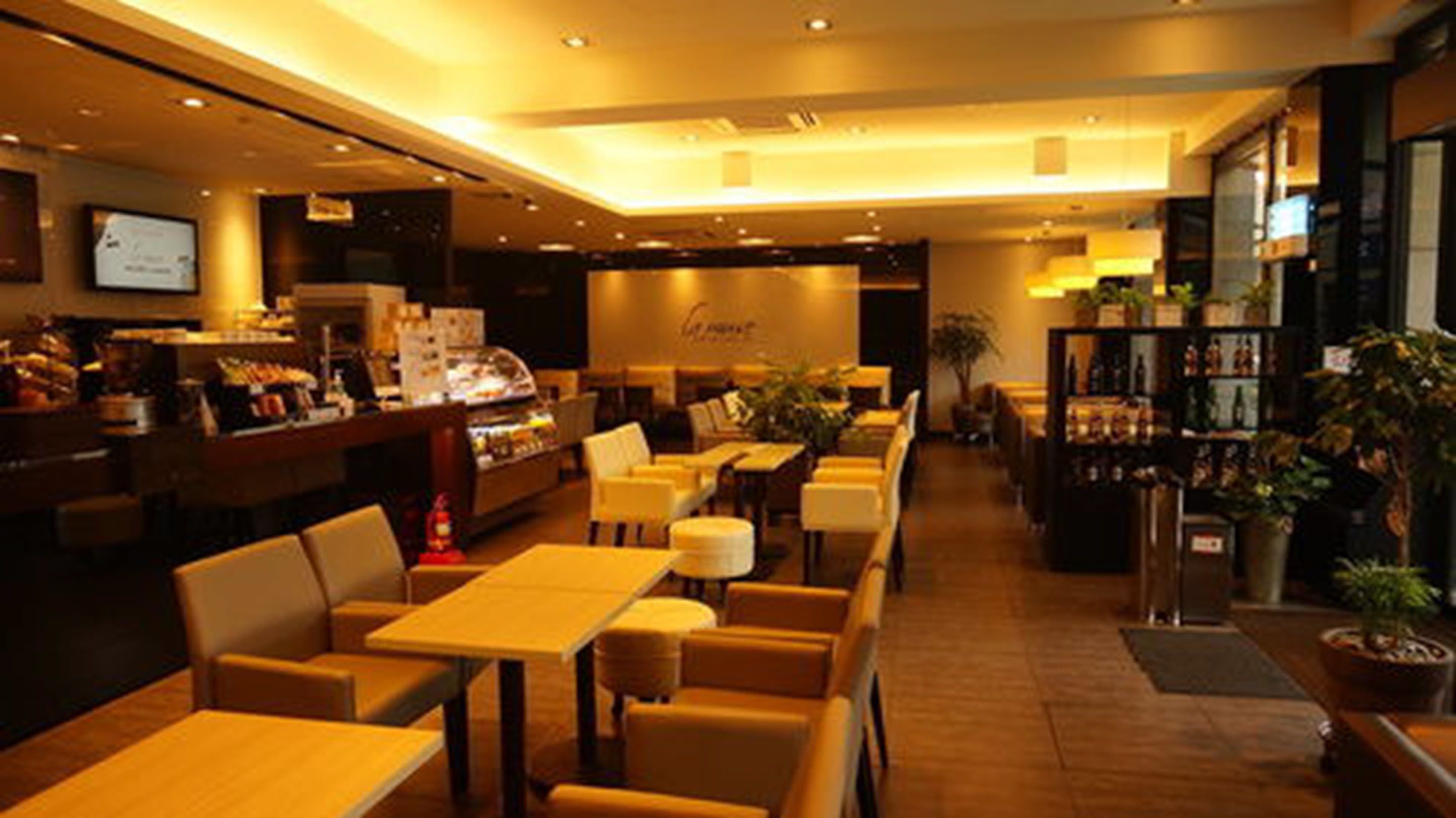 Un restaurante con varias mesas y sillas, un mostrador con productos alimenticios y una zona de bar.