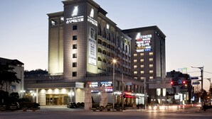 Een hotel met meerdere verdiepingen, een opvallende ingang en verlichte borden.