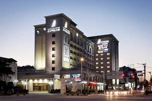Un hotel de varios pisos, con una entrada destacada y letreros iluminados.