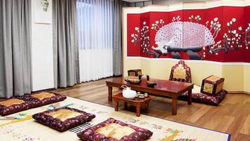 Una tradizionale stanza giapponese con pavimento in tatami, un tavolino in legno e un paravento scorrevole rosso decorato con un motivo di pavone.