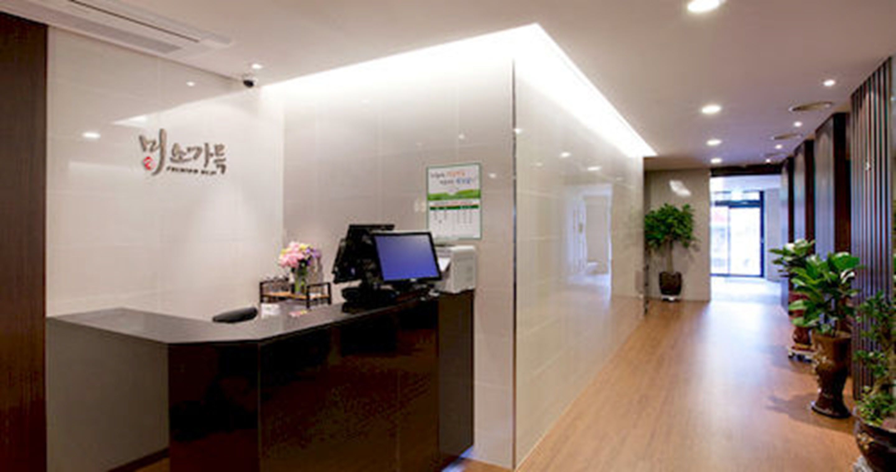 A reception desk with a computer, a sign, and a potted plant.