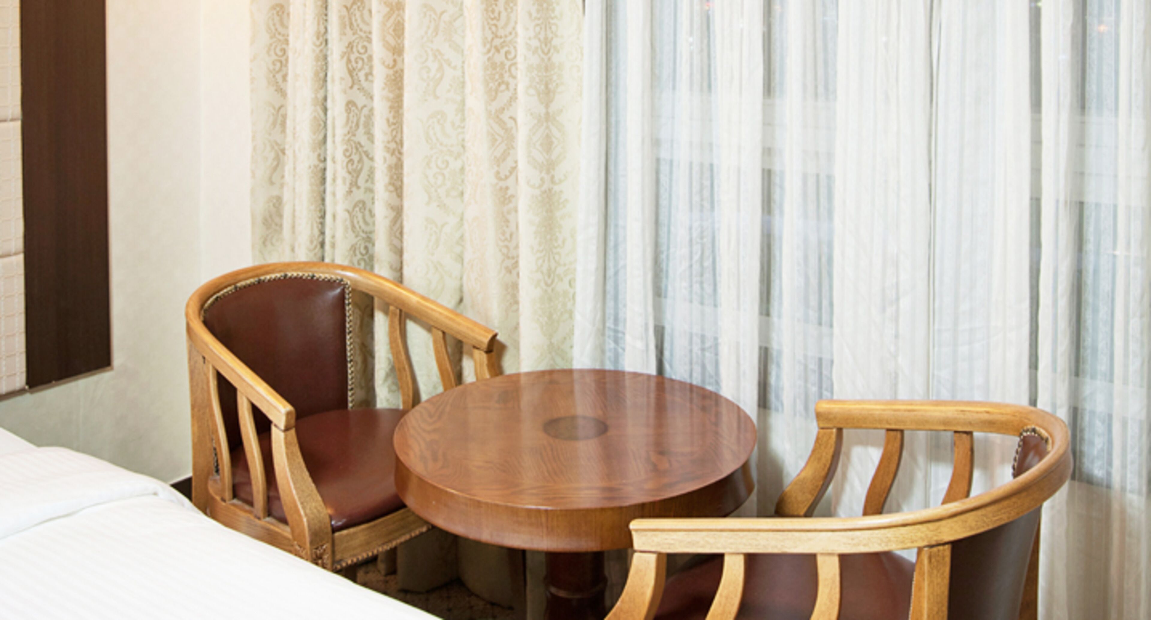 Una habitación de hotel con una mesa redonda de madera y dos sillas de madera.