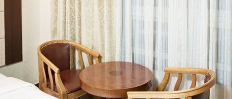 Una habitación de hotel con una mesa redonda de madera y dos sillas de madera.