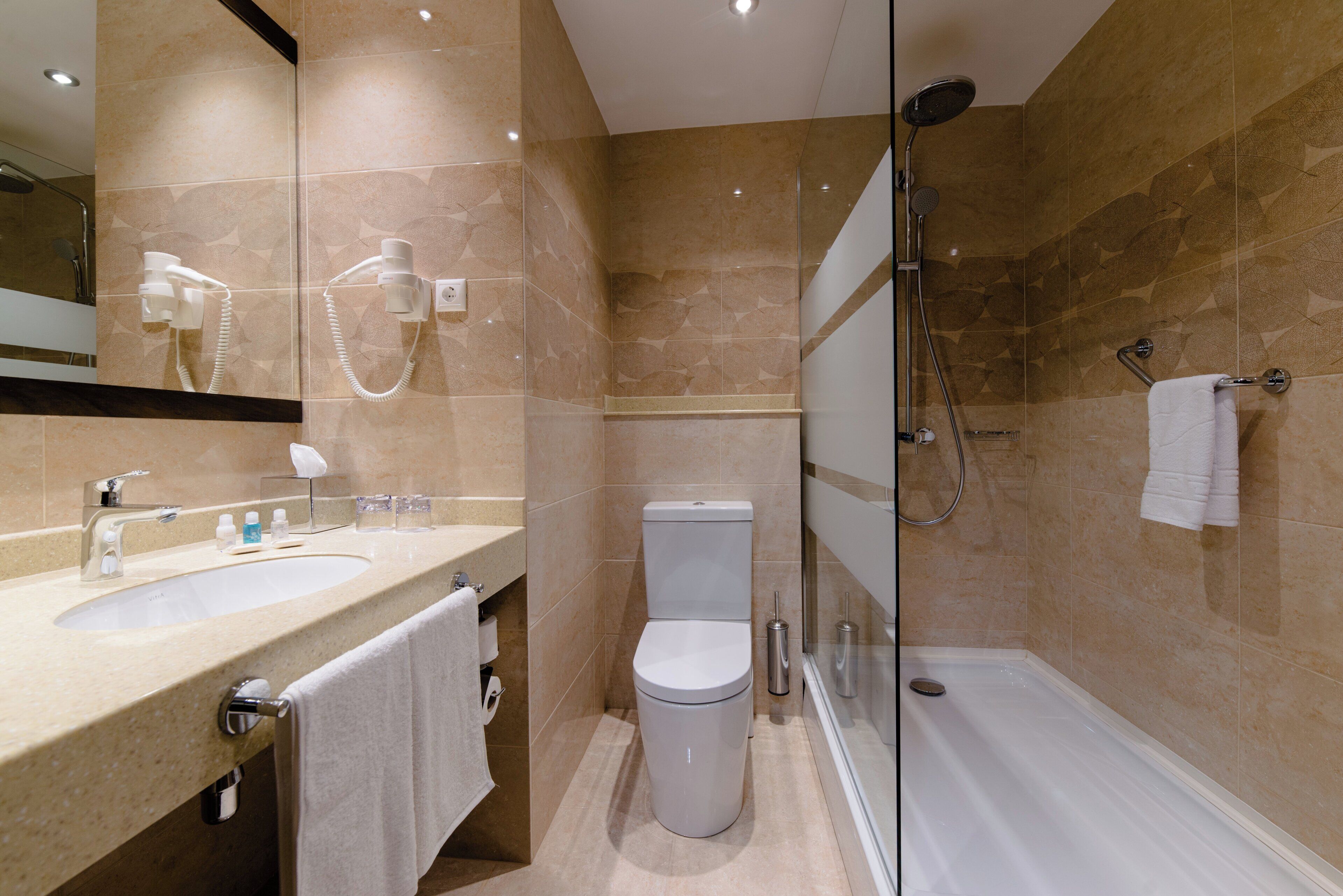 A modern bathroom with a sink, toilet, and shower.