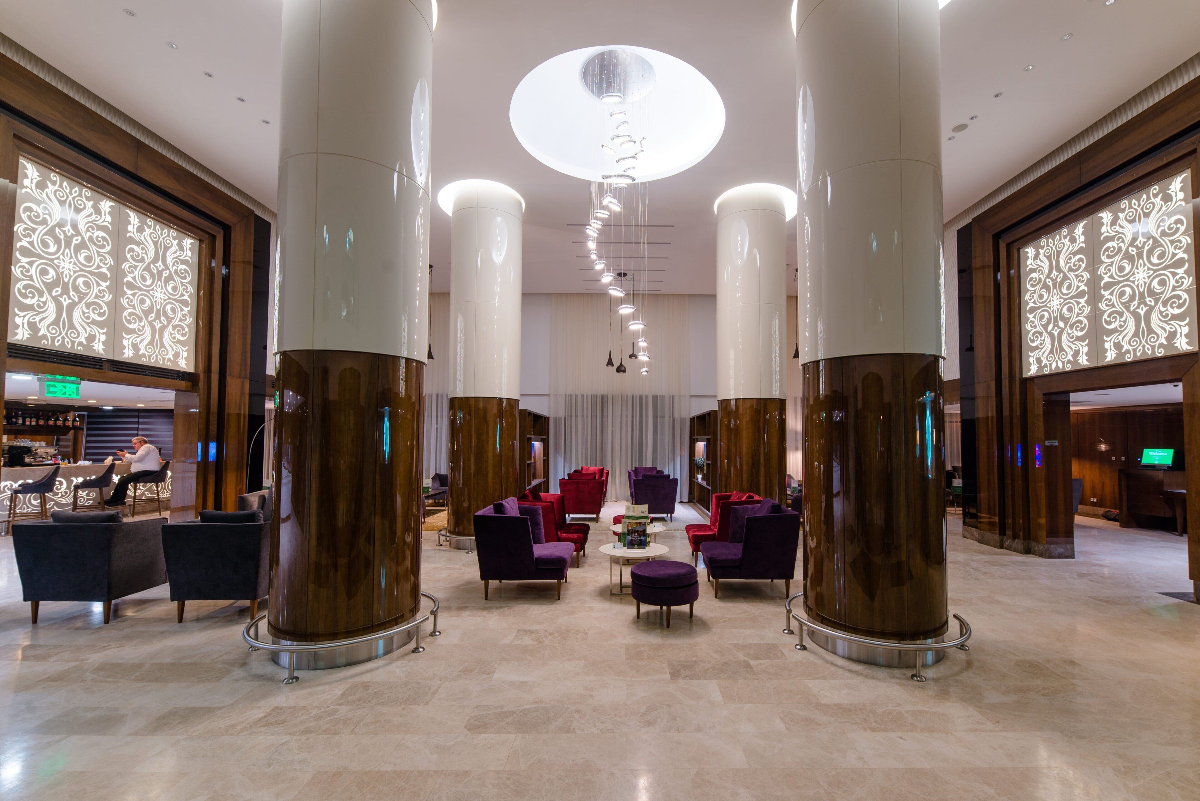 A spacious lobby with high ceilings, large columns, and a central seating area with purple chairs.