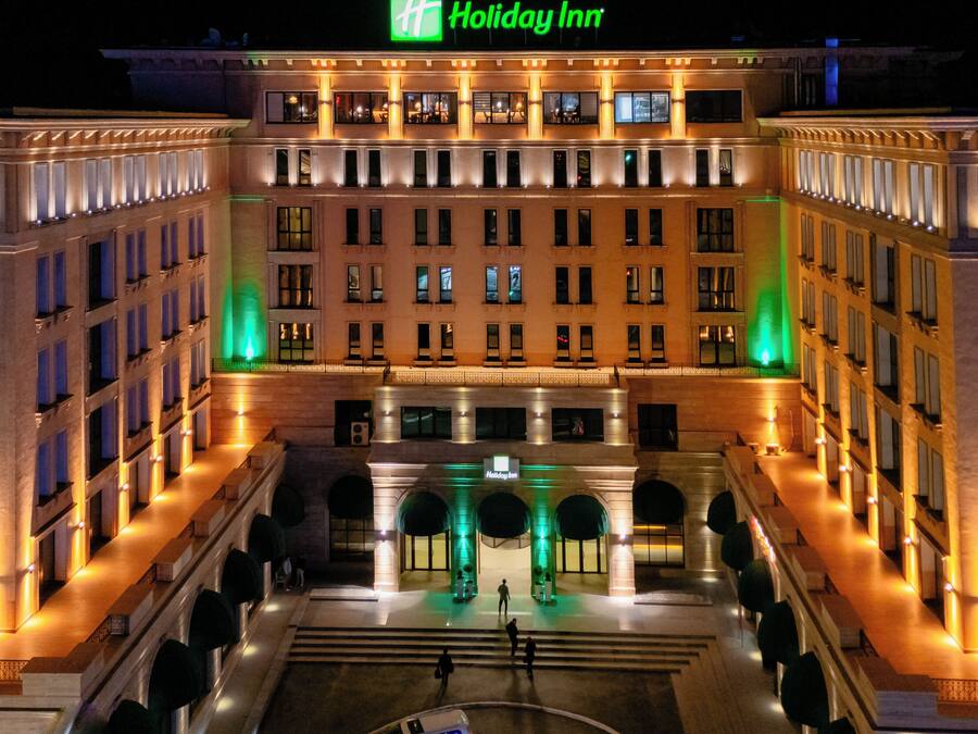 A Holiday Inn hotel with a symmetrical facade, multiple floors, and a central courtyard with a fountain.