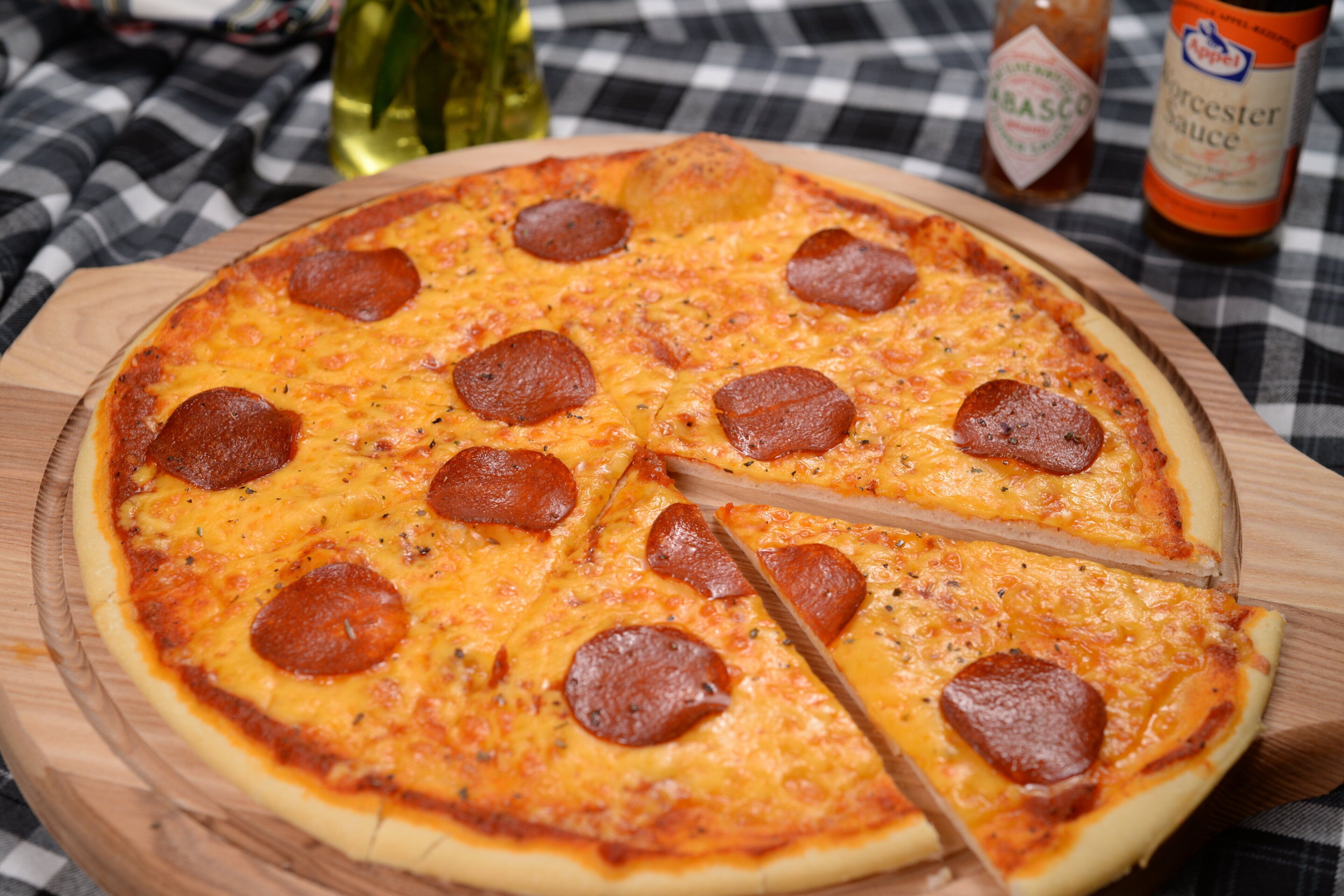 Pizza amb làmines de pepperoni sobre un tauler de fusta.