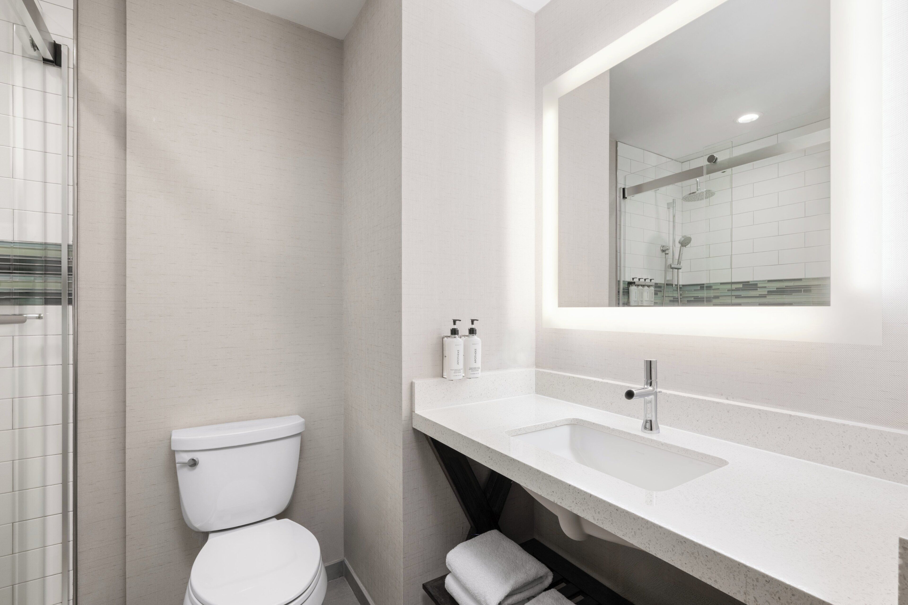 A modern bathroom with a white toilet, a sink, and a shower area.