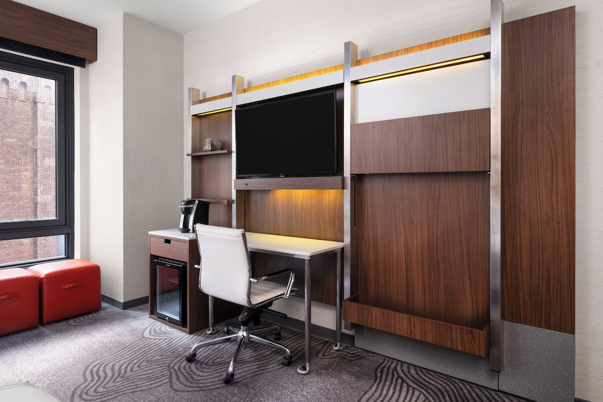 A modern office space with a desk, chair, and a large flat-screen TV mounted on a wooden wall.