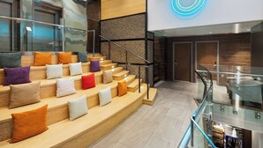 A modern interior with a staircase, glass railing, and a neon light. - EVEN Hotel New York - Times Square South by IHG (New York)
