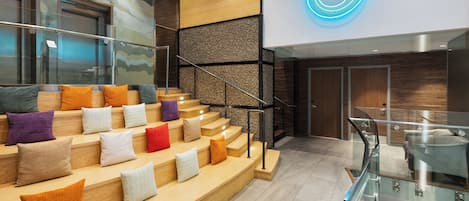 A modern interior with a staircase, glass railing, and a neon light.
