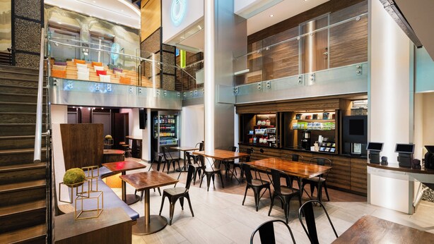 A modern restaurant with a staircase, seating area, and a bar. - EVEN Hotel New York - Times Square South by IHG (New York)
