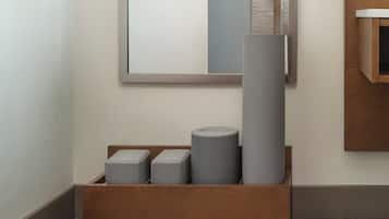 A modern room with a wooden bench, a mirror, and a storage box containing cylindrical objects.