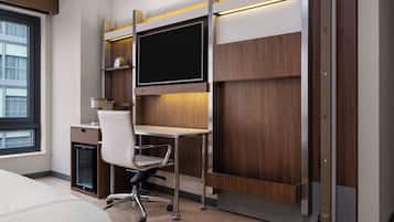 Una habitación de hotel moderna con una cama, un escritorio con una computadora, una silla y un ventanal grande.