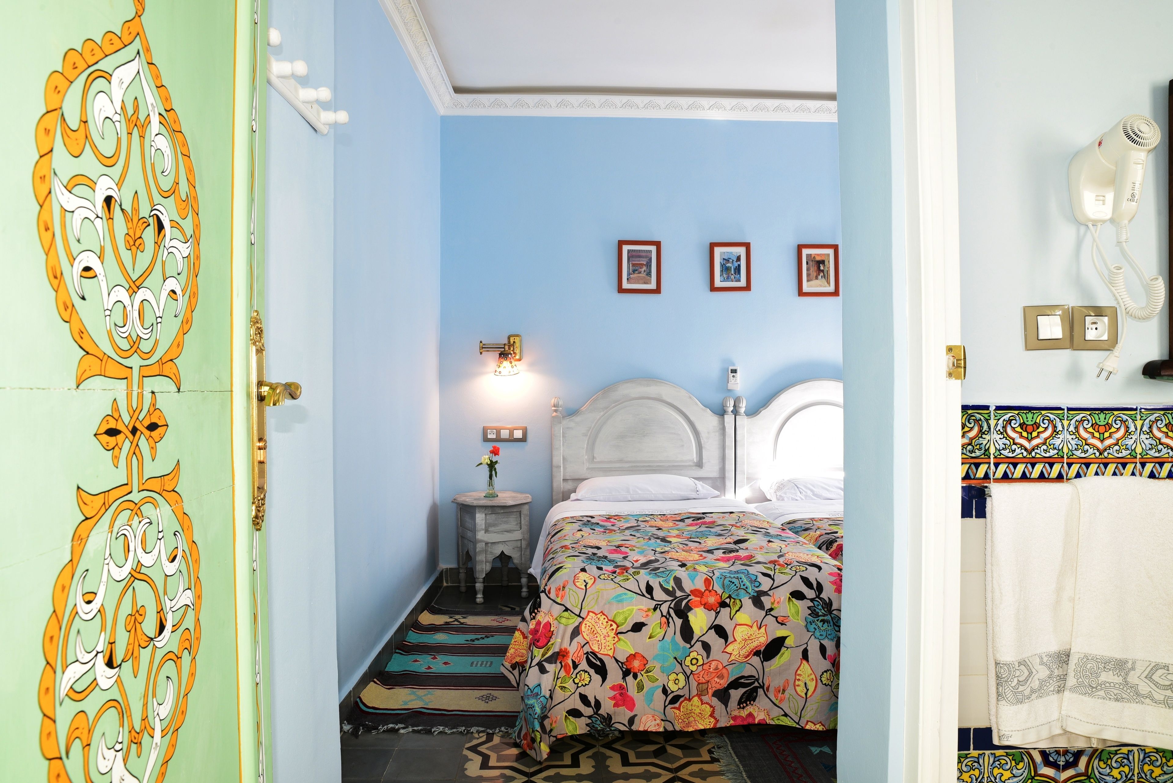 A bedroom with a bed, a nightstand, a wall-mounted lamp, and a door with a decorative design.