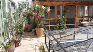 A terrace with potted plants, a wooden pergola, and a glass railing.