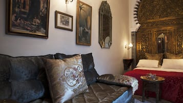 Une pièce comprenant un canapé, un lit et un mur orné de tableaux encadrés.