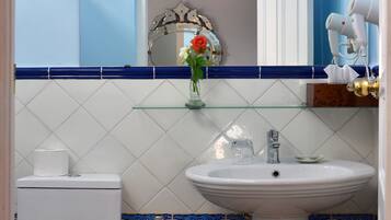 Un baño con inodoro blanco, lavamanos pedestal, espejo y zona de ducha.