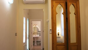 A hallway with a wooden door, a tiled floor, and a ceiling light fixture.