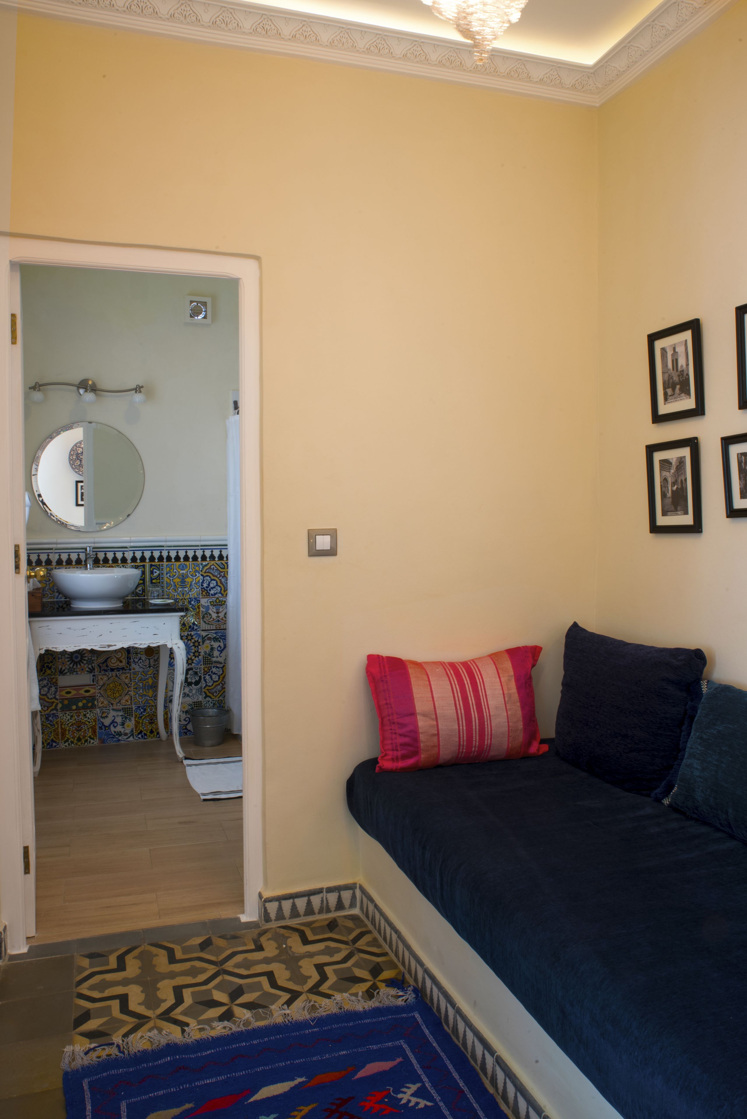 Un dormitorio con cama, mesita de noche, cómoda, espejo y puerta que da a un baño.