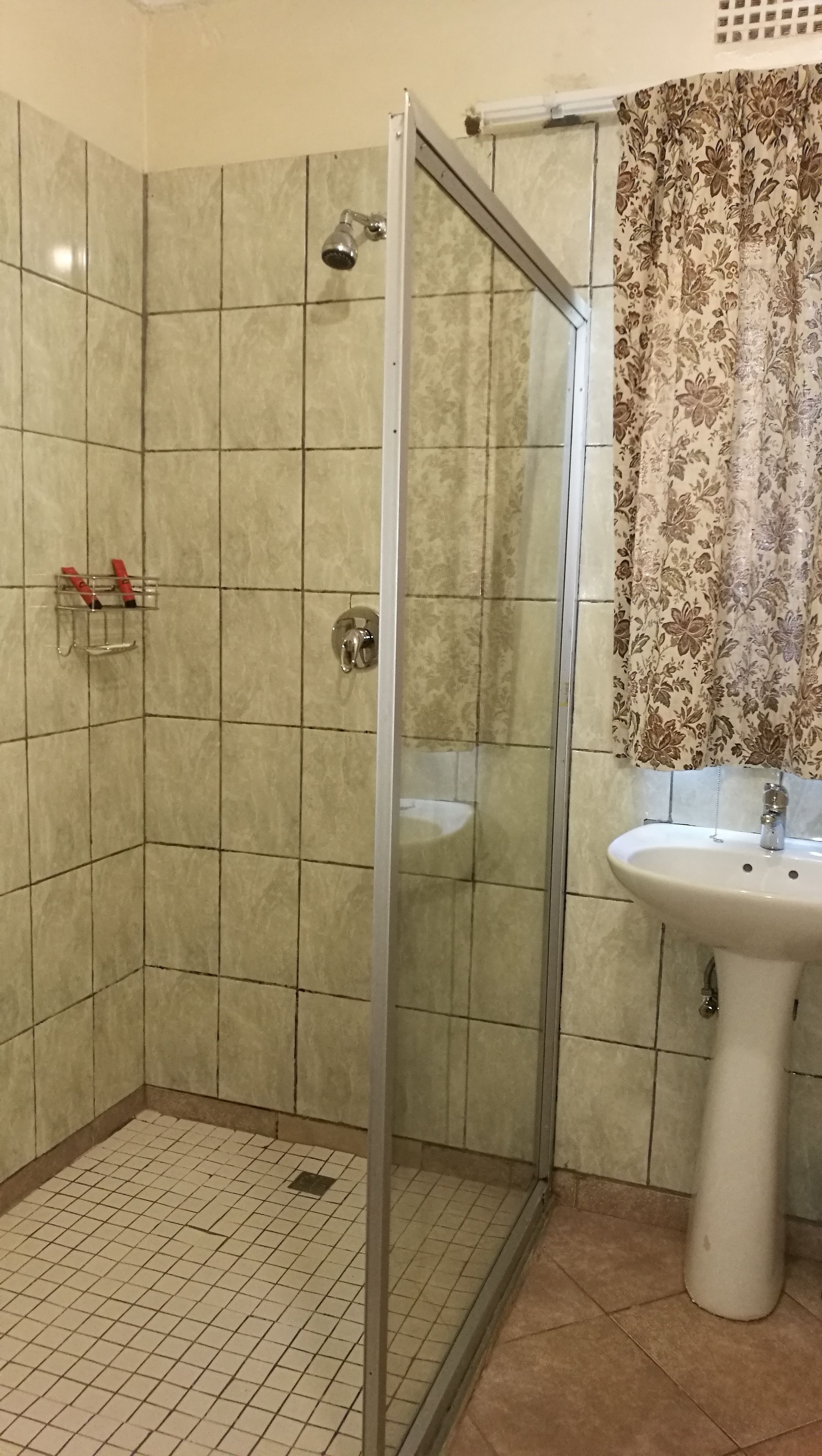 A bathroom with a glass shower enclosure, a sink, and tiled walls.