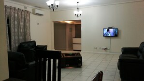 A living room with a television mounted on the wall, a coffee table, and two black leather sofas. - LePatino Bed & Breakfast (Livingstone)