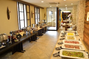 A buffet setup with various food items and cooking equipment.