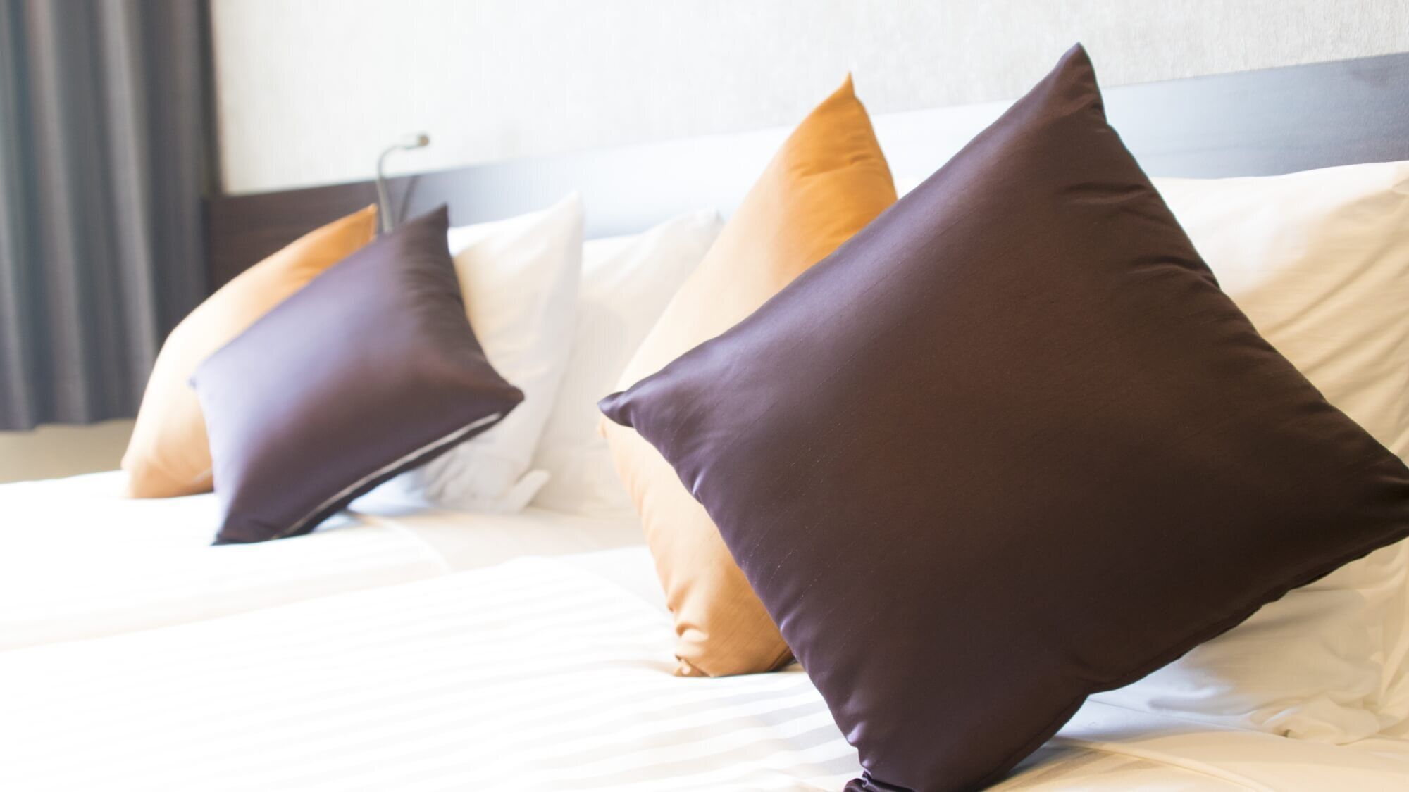 A hotel room with a bed, pillows, and a headboard.