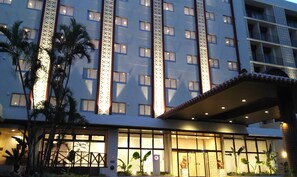 Un hotel con varios pisos, amplias ventanas y una entrada bien iluminada.